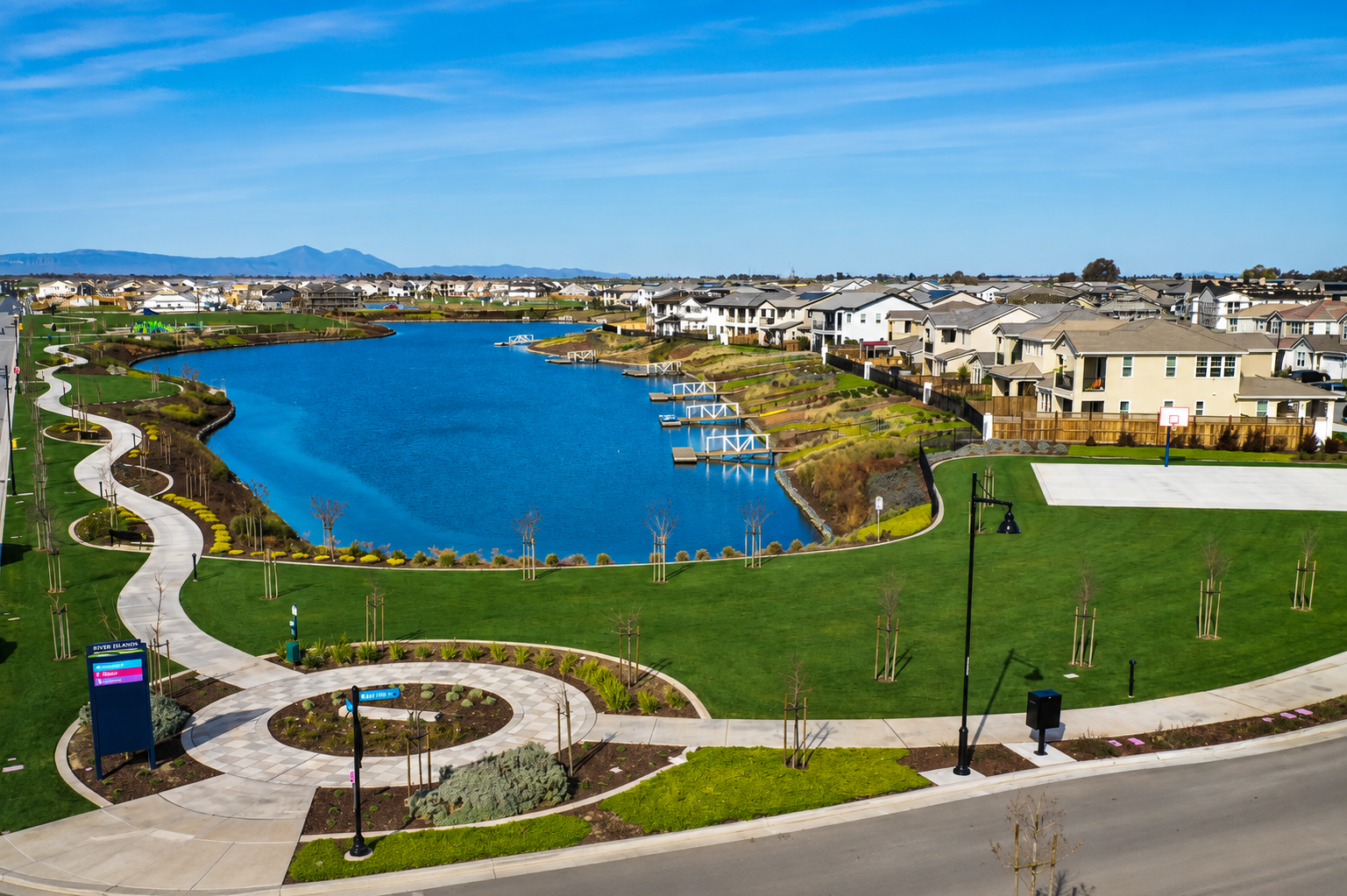 The lake at River Islands, ringed by walking paths, lawn, private docks, and homes